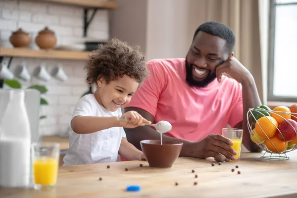 Süßes kleines Mädchen frühstückt mit ihrem Vater und fühlt sich gut, Vater lächelt — Stockfoto