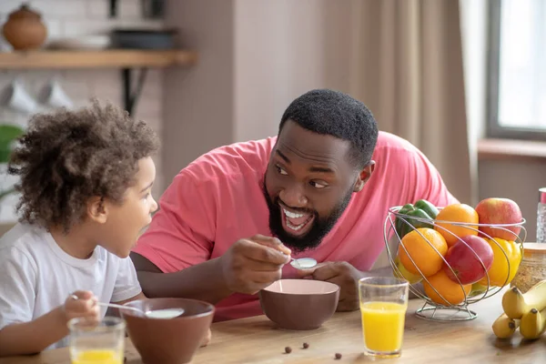 Süßes kleines Mädchen frühstückt mit ihrem Vater und ist amüsiert — Stockfoto