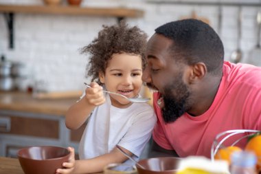 Tatlı küçük kız sakallı, esmer babasını besliyor.