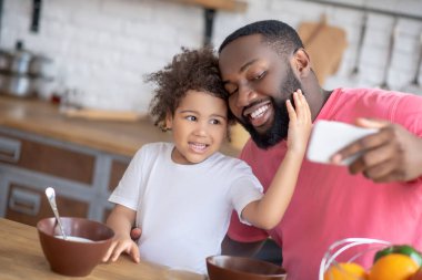 Tatlı küçük kız babasının yüzüne dokunuyor ve ikisi de mutlu görünüyor.