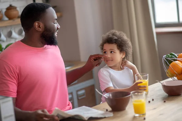 Темноволосий афроамериканський батько торкається його дочок щоки і посміхається — стокове фото