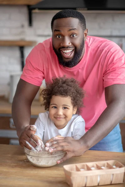 Hombre barbudo guapo de piel oscura que parece feliz divirtiéndose con su hija —  Fotos de Stock