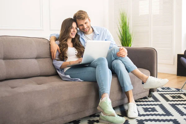 Young couple in denim sitting on a sofa and watching a movie — Stock Photo, Image