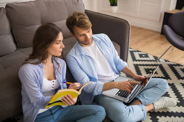 Young couple looking interested, man showing something on a laptop — Stock Photo, Image