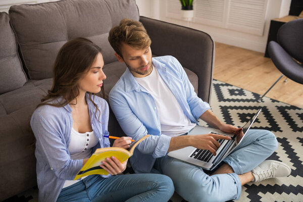 Young couple looking interested, man showing something on a laptop