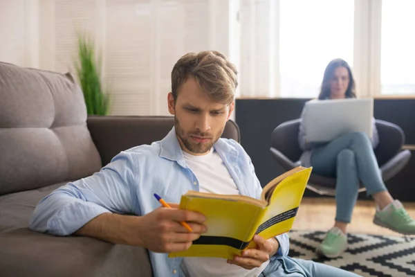 Joven involucrado estudiando antes del examen, su esposa sentada detrás de él — Foto de Stock