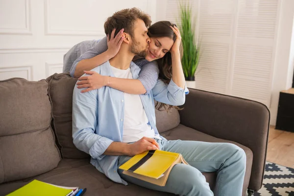 Young man studying before exam, his wife hugging him — Stock Photo, Image