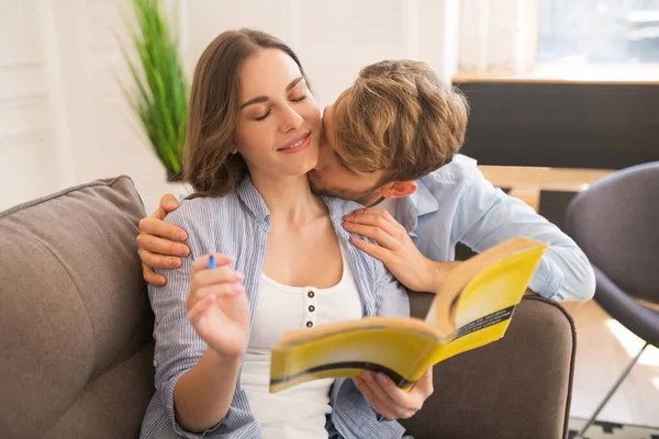 Young woman studying before exam, her husband kissing her — Stock Photo, Image