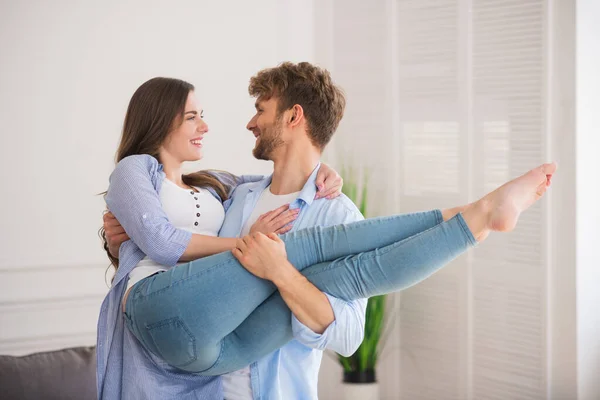 Joven sosteniendo a su esposa y sonriendo felizmente — Foto de Stock