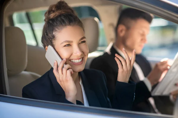 Mujer sonriente con éxito hablando en un teléfono inteligente en un coche — Foto de Stock