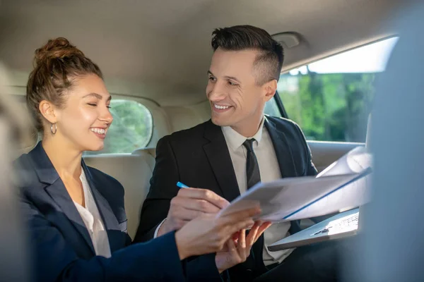 Homem feliz e mulher assinar documento no carro — Fotografia de Stock