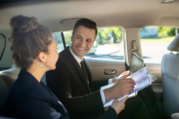 Attractive man signing document and woman in car — Stock Photo, Image