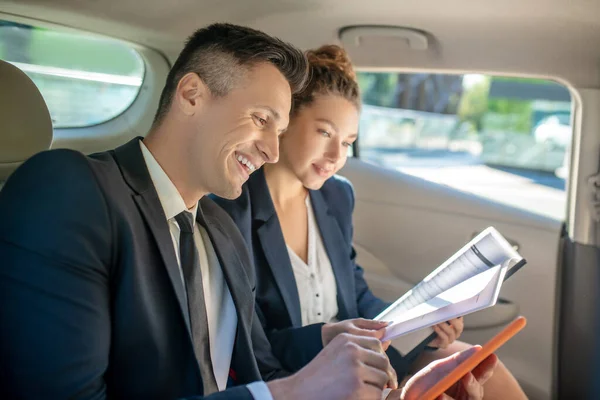 Muž s tabletem a žena diskutovat o podnikání v autě. — Stock fotografie