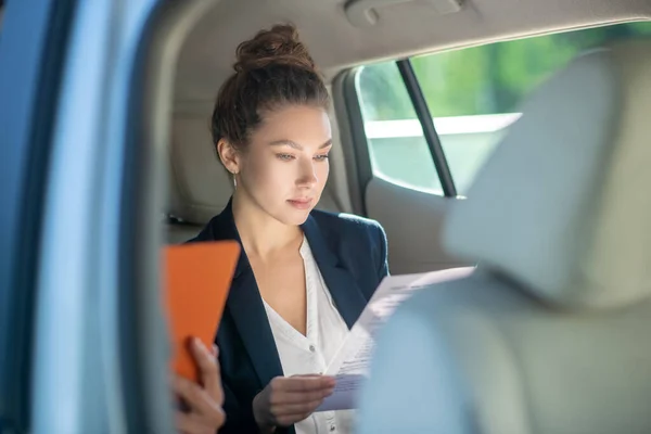 Serious business woman studying a document in a car. — Stock Photo, Image