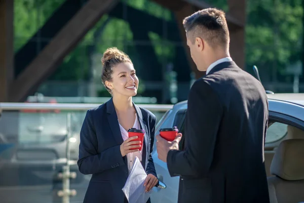 Mulher de sucesso com café e papéis e homem de pé — Fotografia de Stock