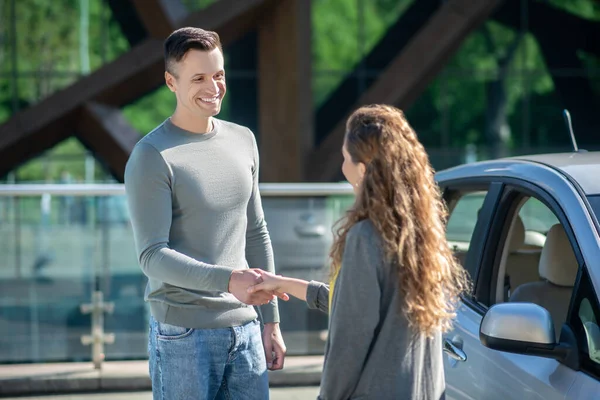 Vysoký pohledný muž dává klíčky od auta k dlouhovlasé ženě — Stock fotografie