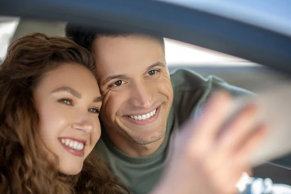 Jovem casal sentado no carro e fazendo selfie — Fotografia de Stock