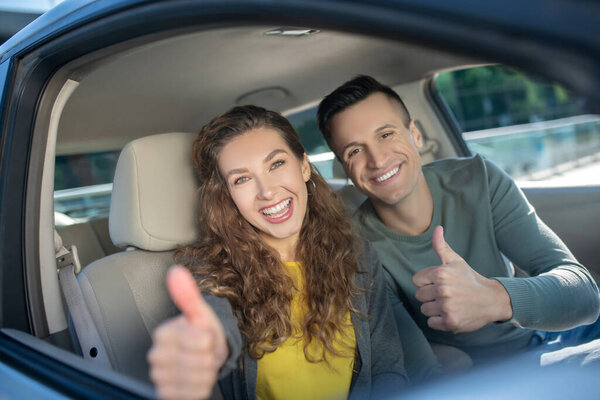 Young couple sitting in the car and feeling amazing