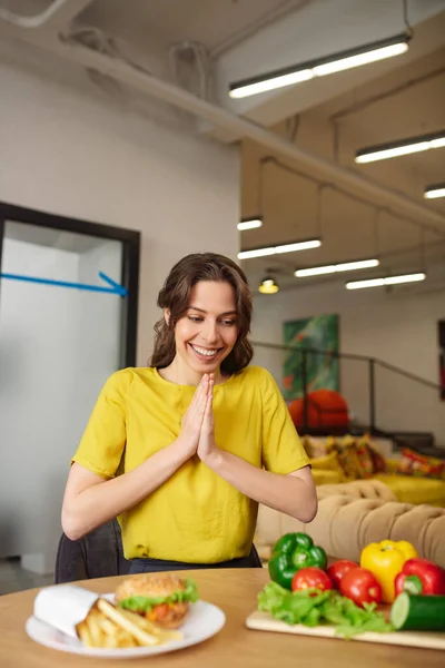 Радоваться молодой девушке в желтой блузке, глядя на свежие овощи — стоковое фото