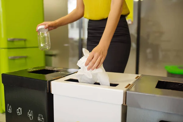 Kvinnliga händer håller en burk och papper över papperskorgar — Stockfoto