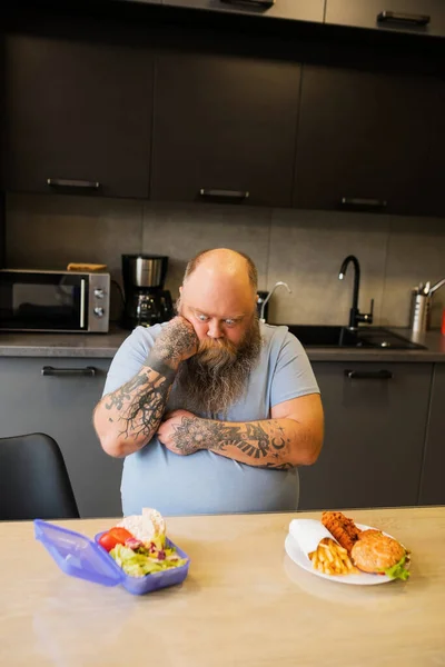 Hombre barbudo con grandes ojos eligiendo un bocadillo —  Fotos de Stock