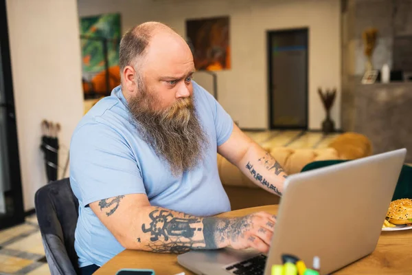 Bald bearded man sitting at a laptop