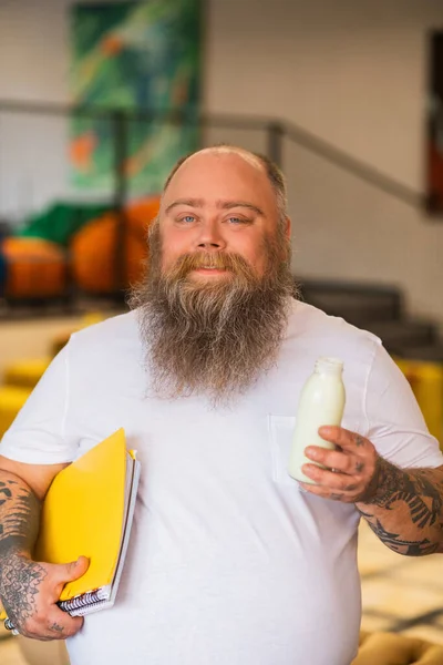 Calvo barbuto grassoccio uomo aprire una bottiglia con latte e sorridente — Foto Stock