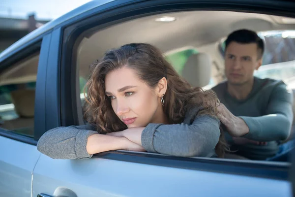 Offended turned away woman and attentive man sitting in car