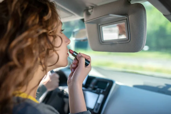 Jovem mulher pintando lábios em um carro — Fotografia de Stock