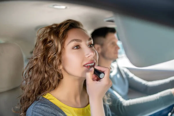 Mulher bonita pintando lábios no assento do passageiro no carro — Fotografia de Stock