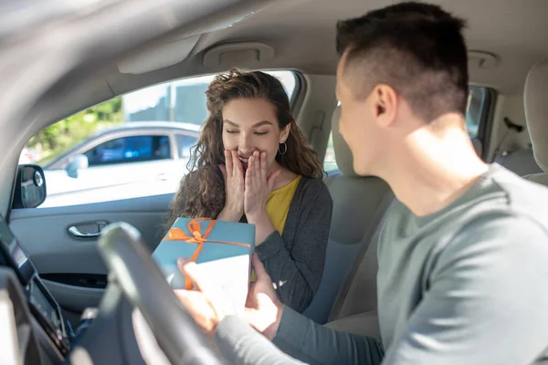 Joyful surpreendido mulher e homem com caixa no carro — Fotografia de Stock