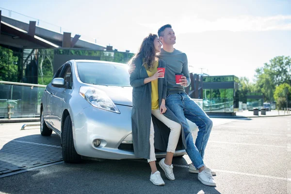 Mann und Frau stehen an sonnigem Tag neben Auto mit Kaffee — Stockfoto