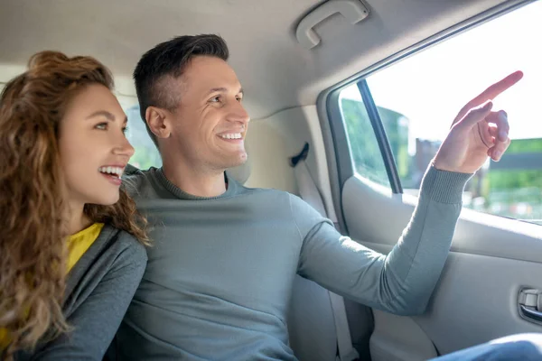 Jovem adulto cara e menina sentado no banco de trás no carro — Fotografia de Stock