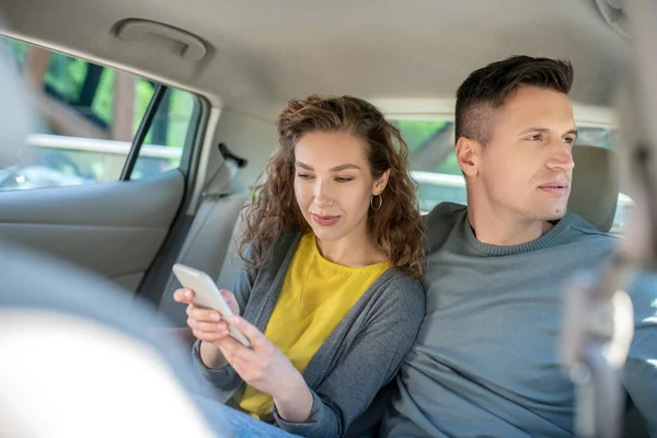 Donna con smartphone e uomo che guarda fuori dalla finestra — Foto Stock