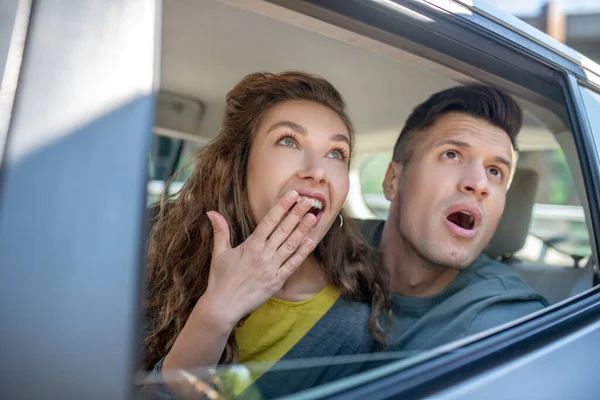 Velmi překvapený muž a žena vyhlížející z auta. — Stock fotografie