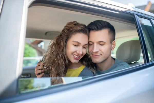 Jovens amantes homem e mulher com olhos fechados em um carro — Fotografia de Stock