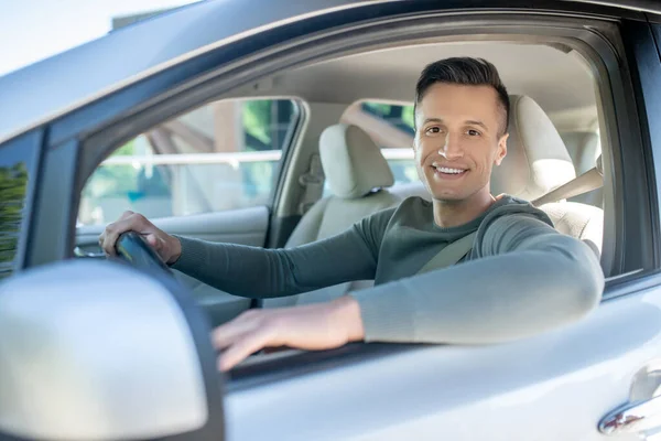 Joyful young man sitting in car on the drivers seat — Stock Photo, Image