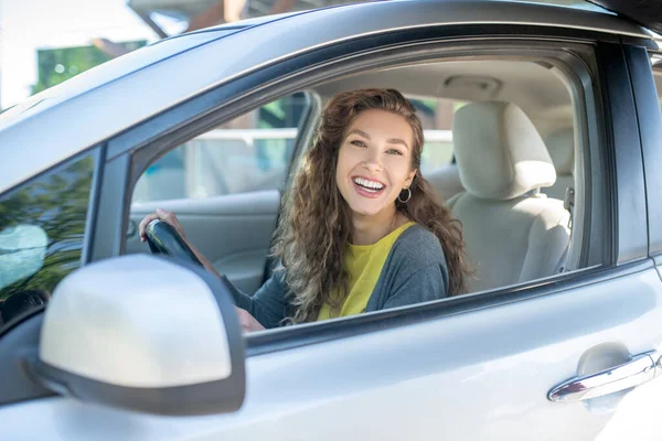 Sorrindo jovem mulher adulta sentada em um carro . — Fotografia de Stock