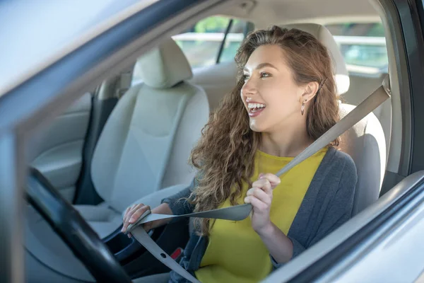 Smiling young woman holding hands on seat belt — Stock Photo, Image