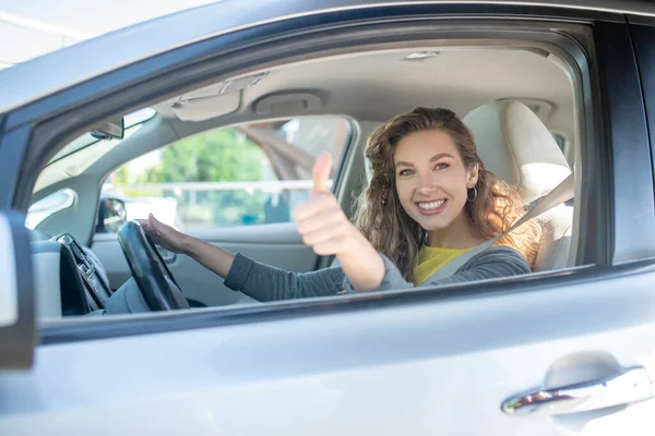 Mujer sonriente satisfecha conduciendo coche mostrando ok — Foto de Stock