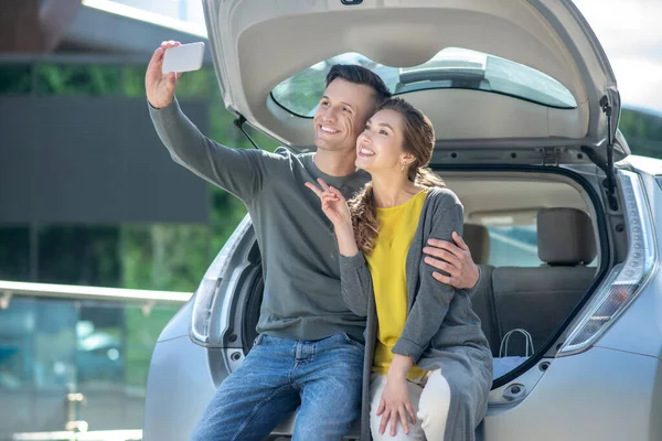 Homem e mulher tomando selfie perto do carro — Fotografia de Stock
