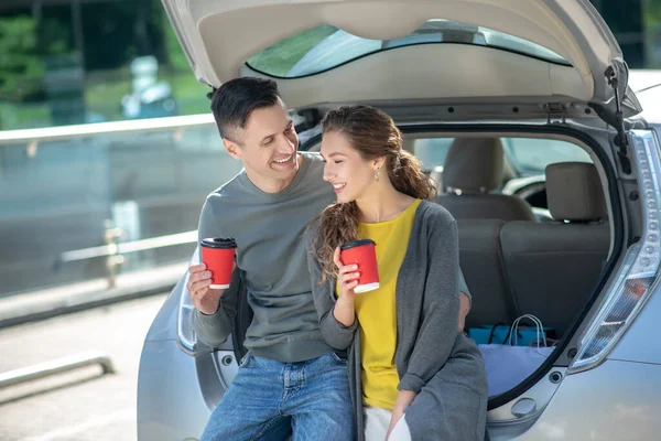 Чоловік і жінка мають каву біля своєї машини . — стокове фото