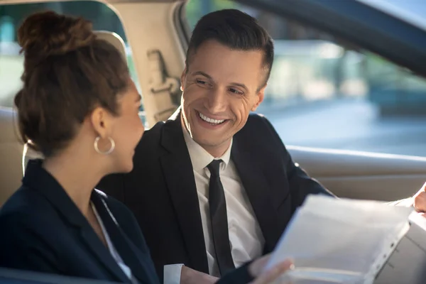 Hombre y mujer llevando a cabo negociaciones de negocios en un coche — Foto de Stock