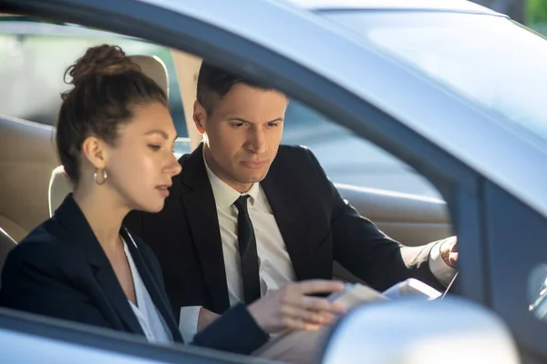 Homem e mulher sérios com documentos em um carro — Fotografia de Stock
