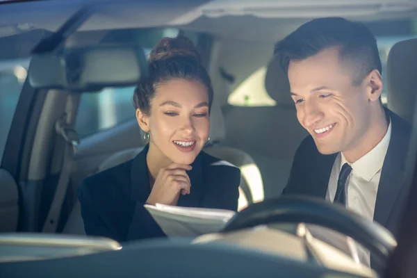 Mladá úspěšná žena a muž recenzi dokumentů v autě — Stock fotografie