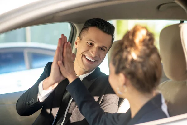 Usmívající se muž a žena dotýkající se dlaně v autě — Stock fotografie