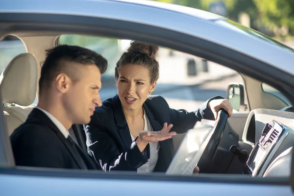 Sério gestual mulher dirigindo e um homem em um carro — Fotografia de Stock