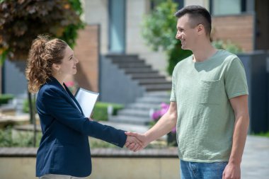 Zarif bir iş kadını bir müşteriyle el sıkışıyor ve gülümsüyor.