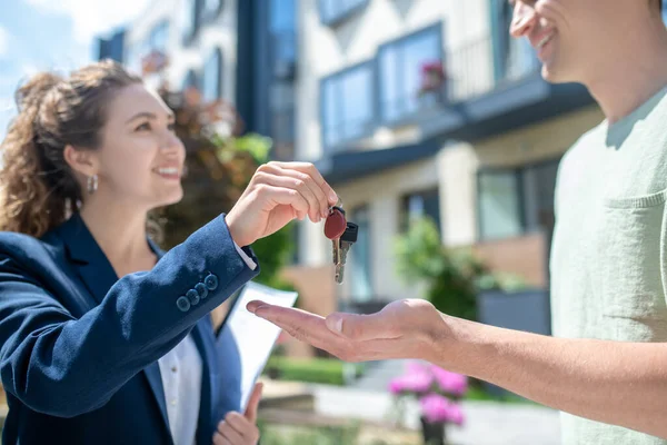 Smiling female broker giving the apartment keys to the client