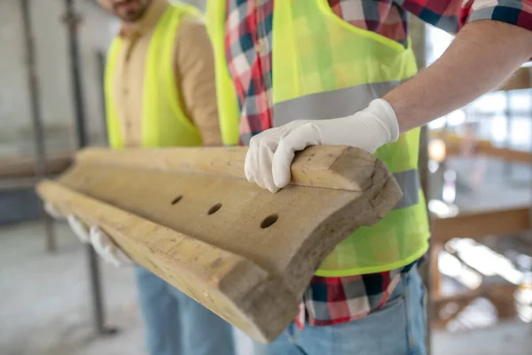 Close-up van bouwvakkers handen in handschoenen die zware houten planken bij elkaar houden — Stockfoto